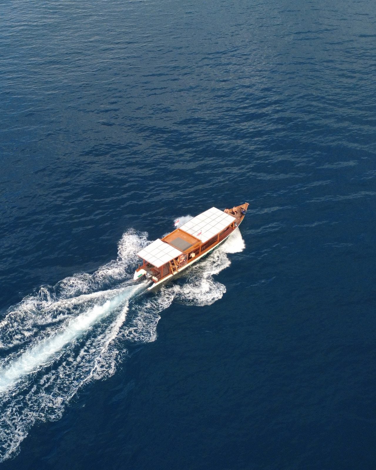 Aerial view of the Moana boat leaving a white wake on dark blue water